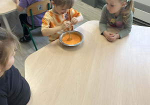 Chłopiec mieszający magiczną farbę w metalowej misce przy stoliku