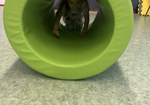 Dziewczynka przechodząca przez materac - tunel na sali gimnastycznej