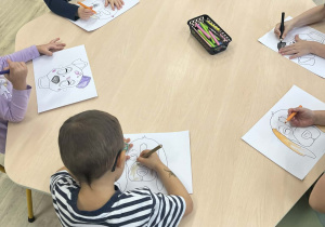 Dzieci przy stolikach kolorujący maski w kształcie psa