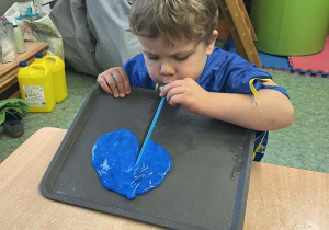 Chłopiec dmuchający rurką w masę slime