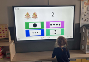 Dziecko rozwiązujące zadanie matematyczne na tablicy interaktywnej