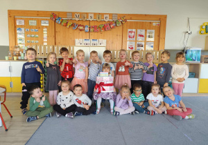 Zdjęcie grupowe w sali z dziewczynką obchodzącą urodziny