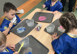 Dzieci siedzący przy stolikach podczas warsztatów z tworzenia slime