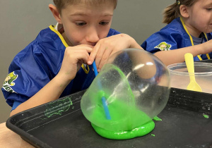 Chłopiec nadmuchuje balon z własnoręcznie stworzonej masy sensorycznej