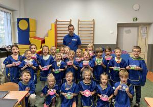 Dzieci i Pan prowadzący warsztaty pozują do zdjęcia z własnoręcznie wykonanymi masami sensorycznymi