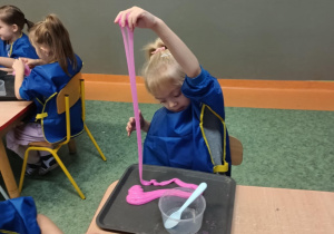 Dziewczynka robi spadający wodospad z własnoręcznie uformowanej masy sensorycznej