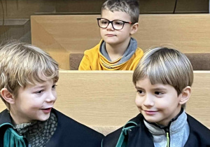Chłopcy siedzą w ławach sądowych