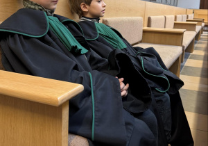 Chłopcy w roli obrońców siedzą w ławie sądowej podczas symulowanej rozprawy