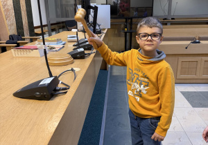 Chłopiec uderza młotkiem sędziowskim