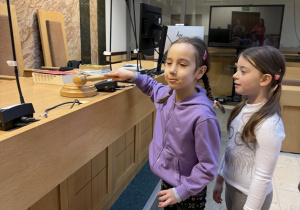 Dziewczynka uderza młotkiem sędziowskim