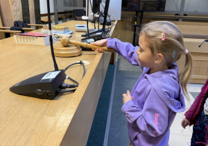 Dziewczynka uderza młotkiem sędziowskim