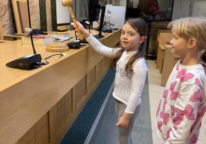Dziewczynka uderza młotkiem sędziowskim