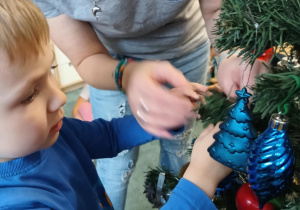 Chłopiec zawiesza ozdoby na choince