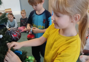 Dzieci zawieszają ozdoby na choince