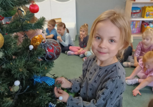 Dziewczynka zawiesza ozdoby na choince