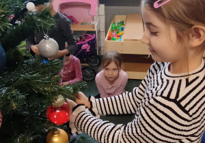 Dziewczynka zawiesza ozdoby na choince