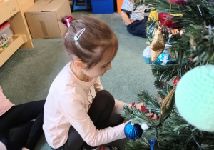 Dziewczynka zawiesza ozdoby na choince