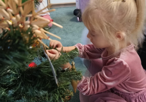 Dziewczynka zawiesza ozdoby na choince