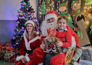 Zdjęcie chłopca pozowane z Mikołajem w świątecznej aranżacji