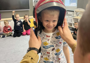 Chłopiec przymierzający kask strażacki