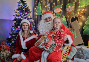 Zdjęcie dziewczynki pozowane z Mikołajem w świątecznej aranżacji