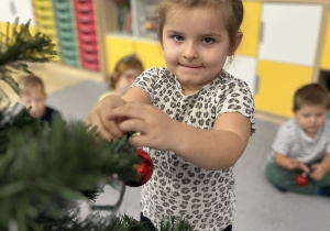 Dziewczynka ubierająca choinkę w klasie