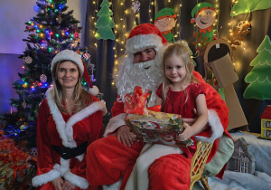 Zdjęcie dziewczynki pozowane z Mikołajem w świątecznej aranżacji