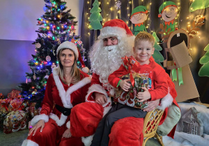 Zdjęcie chłopca pozowane z Mikołajem w świątecznej aranżacji