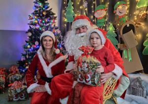 Zdjęcie chłopca pozowane z Mikołajem w świątecznej aranżacji