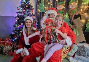 Zdjęcie dziewczynki pozowane z Mikołajem w świątecznej aranżacji