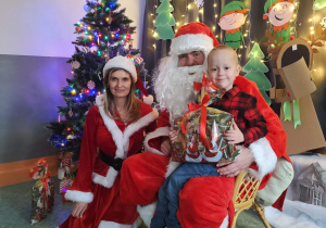 Zdjęcie chłopca pozowane z Mikołajem w świątecznej aranżacji