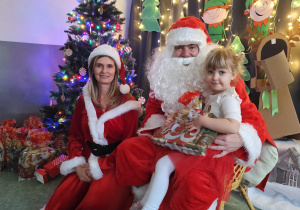 Zdjęcie dziewczynki pozowane z Mikołajem w świątecznej aranżacji