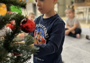 Chłopiec ubierający choinkę w sali
