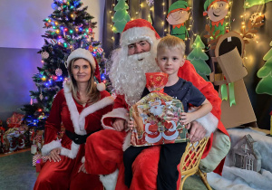 Zdjęcie chłopca pozowane z Mikołajem w świątecznej aranżacji