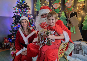 Zdjęcie chłopca pozowane z Mikołajem w świątecznej aranżacji