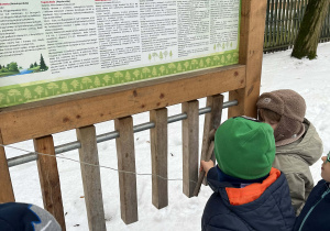 Dzieci przy tablicy edukacyjnej w ogrodzie przedszkolnym
