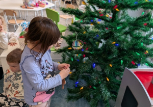 Dziewczynka zakładająca ozdobę choinkową