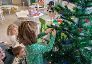 Dziewczynka wieszająca bombkę na choince