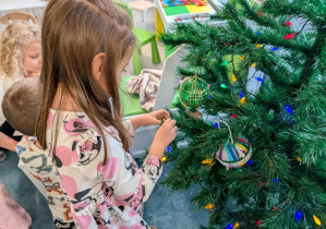 Dziewczynka wieszająca bombkę na choince