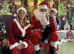 dziecko na kolanach Św. Mikołaja w obecności Pani Mikołajowej