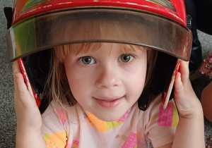 dziewczynka pozuje w kasku strażaka