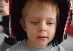 chłopiec pozuje w kasku strażaka