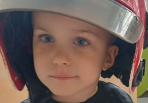 chłopiec pozuje w kasku strażaka