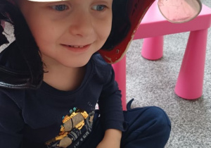 chłopiec pozuje w kasku strażaka