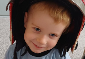 chłopiec pozuje w kasku strażaka