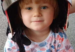 dziewczynka pozuje w kasku strażaka