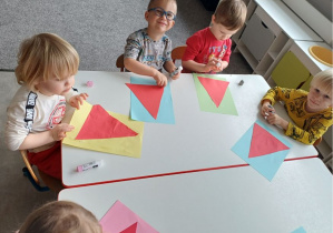 dzieci wykonują pracę plastyczną "Mikołaj"