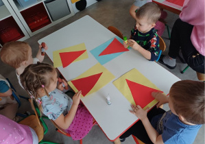 dzieci wykonują pracę plastyczną "Mikołaj"