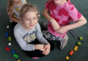 Dziewczynki siedzą w kole zbudowanym z klocków LEGO