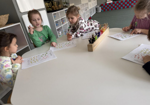 dzieci przy stołach wykonują karty pracy